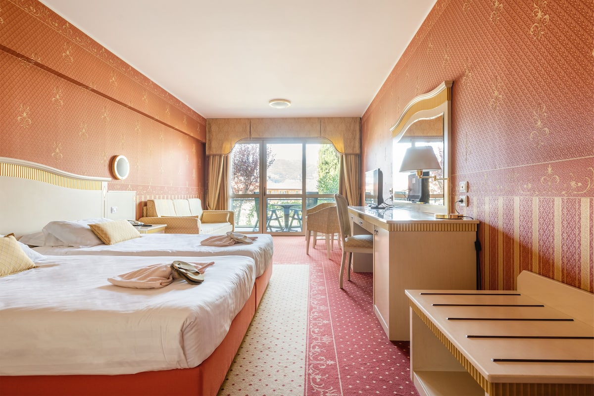 Une chambre d’hôtel avec deux lits, un bureau, une chaise et une vue sur l’extérieur.