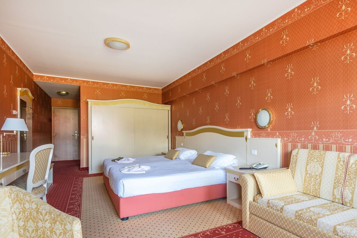 Une chambre d’hôtel avec un lit, un canapé, un bureau et une chaise.