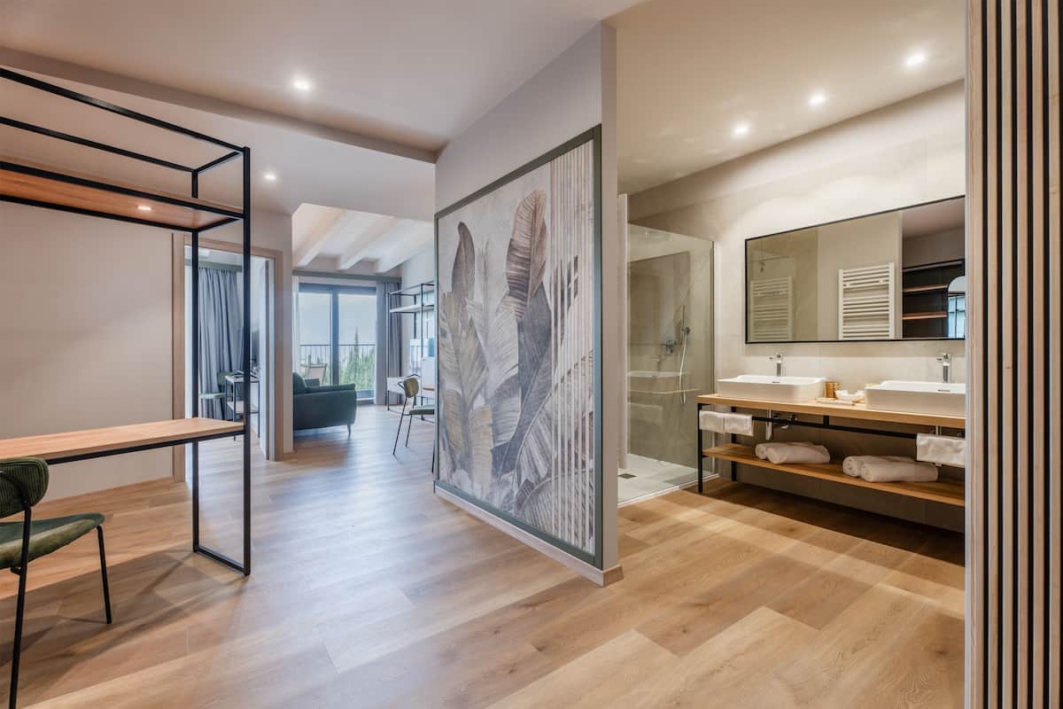 Une salle de bain moderne avec un grand miroir, un revêtement de sol en bois et un espace douche.