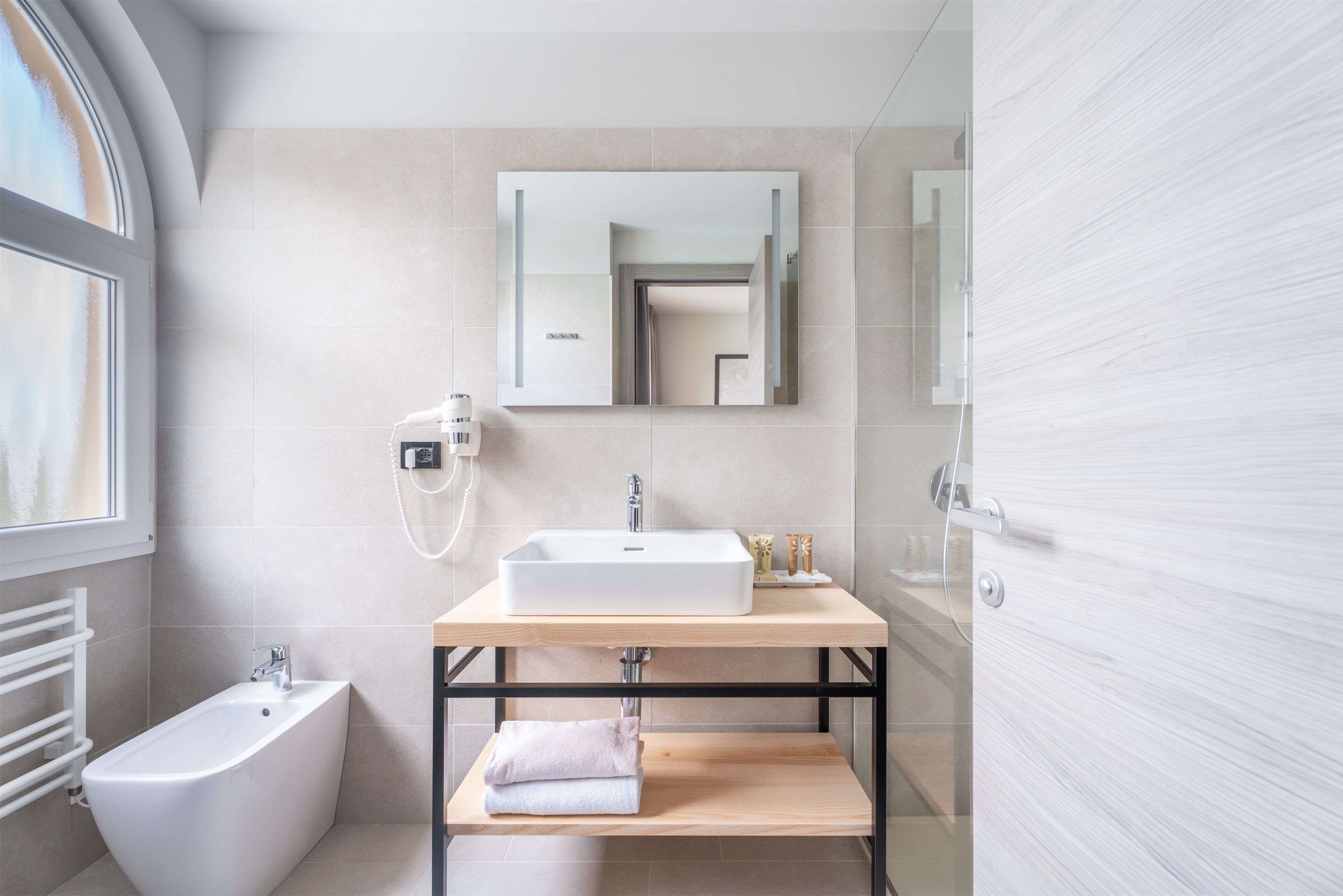 A modern bathroom with a freestanding bathtub, a sink with a mirror above, and a towel rack.