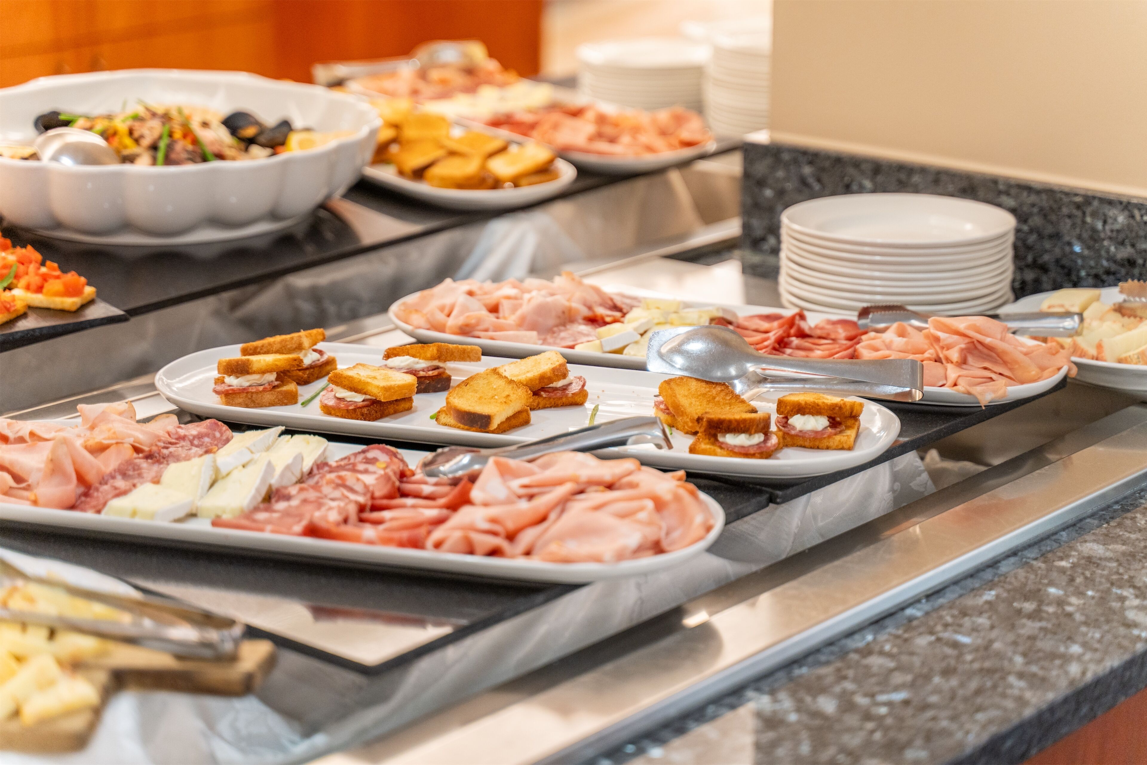 A buffet with various food items including meats, cheeses, and bread.