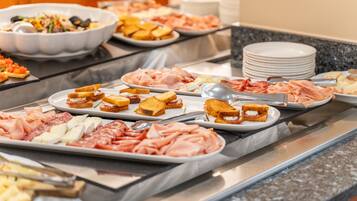 A buffet with various food items including meats, cheeses, and bread.