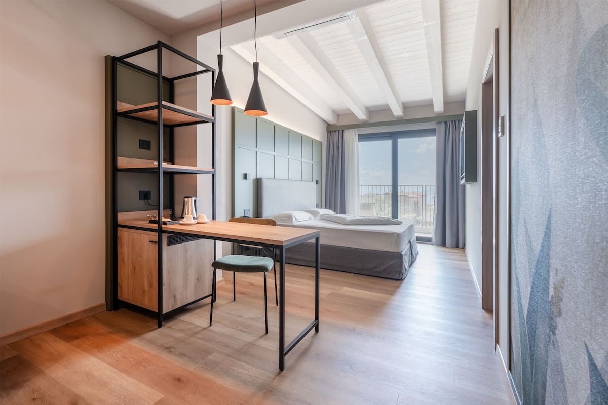 Une pièce moderne et bien éclairée, avec un bureau en bois, une chaise verte et un lit placé devant une grande fenêtre.