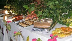 A buffet table with various food items and a cake, surrounded by greenery and flowers. - Hotel Maya (Cap Skirring)