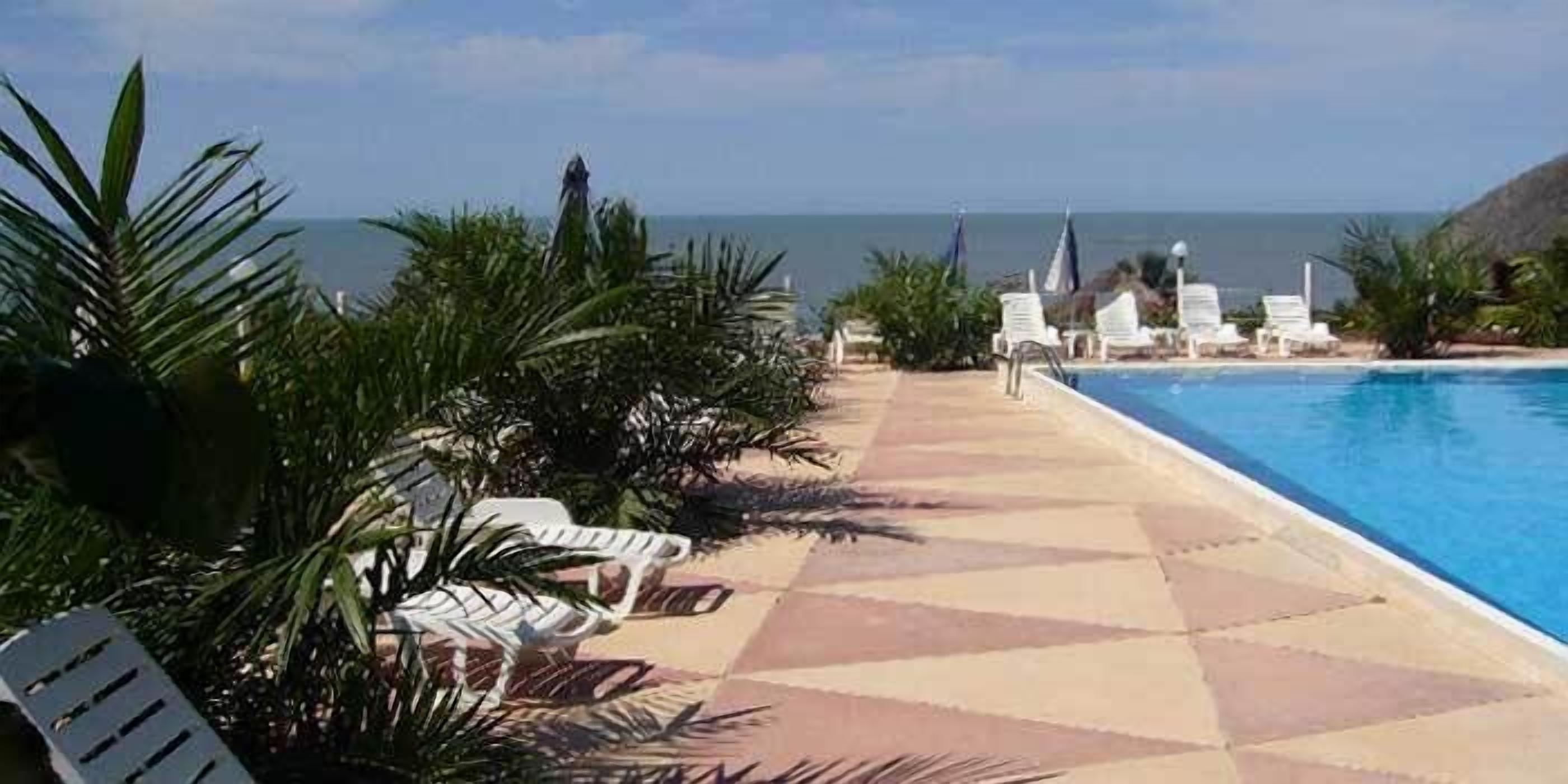 A poolside area with lounge chairs and a view of the ocean.