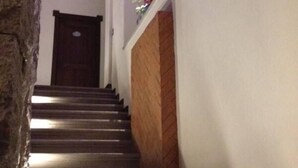 A staircase with a wooden handrail and a white wall with a door at the top. - Hotel Xelhua (San Pedro Cholula)