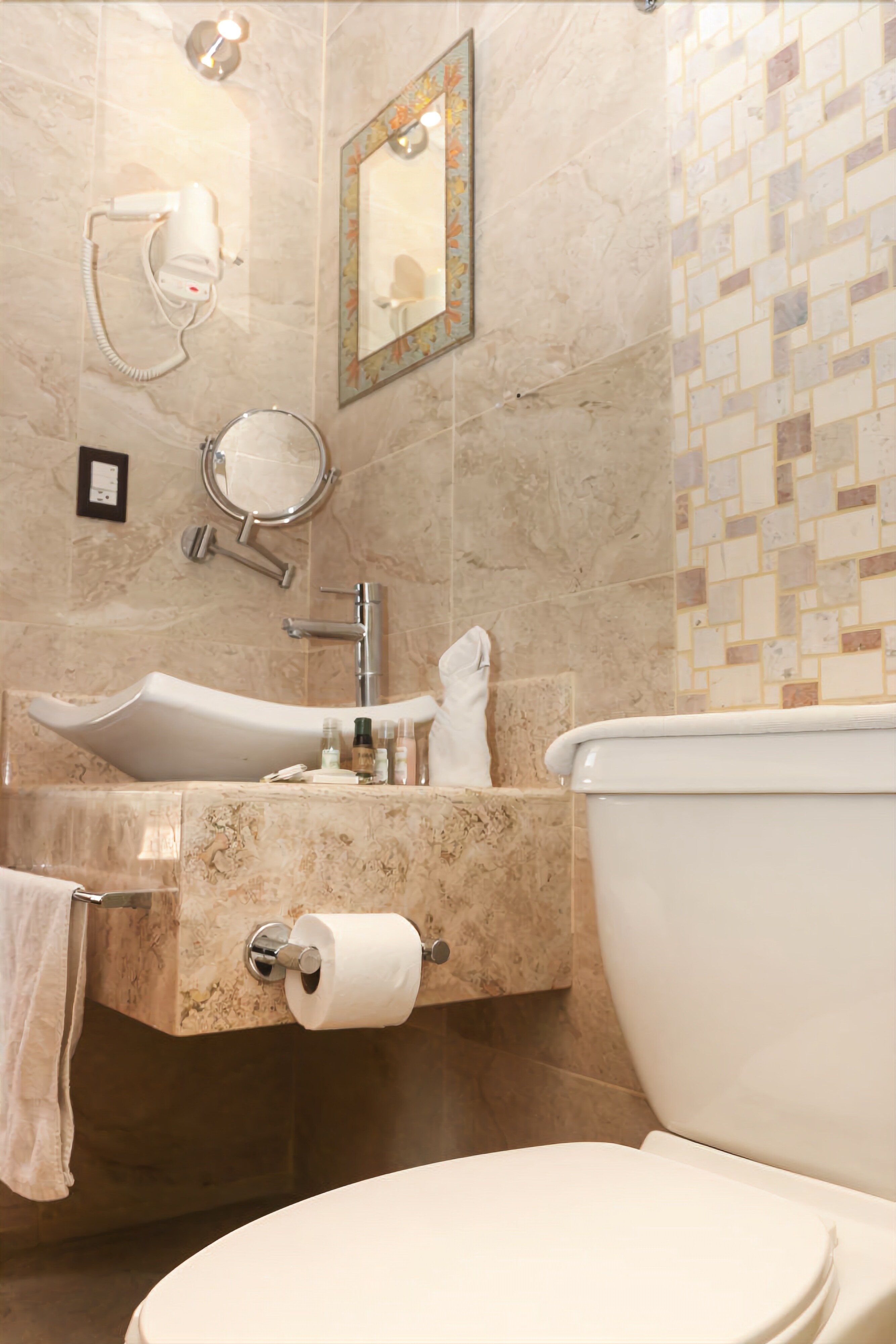 Un baño moderno con lavamanos de mármol, inodoro y espejo.