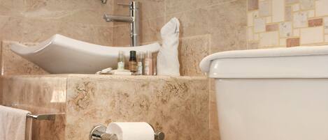 Un baño moderno con lavamanos de mármol, inodoro y espejo.