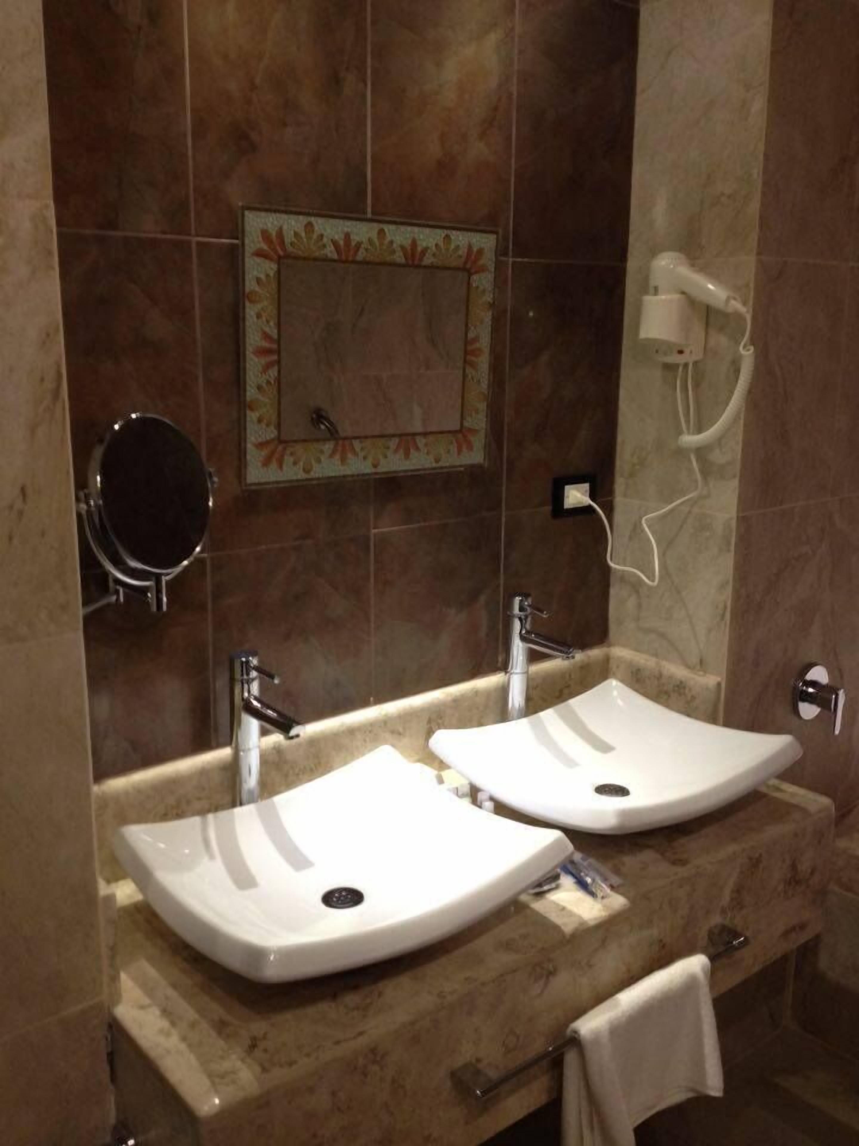 Een badkamer met twee wastafels, een spiegel en een haardroger.