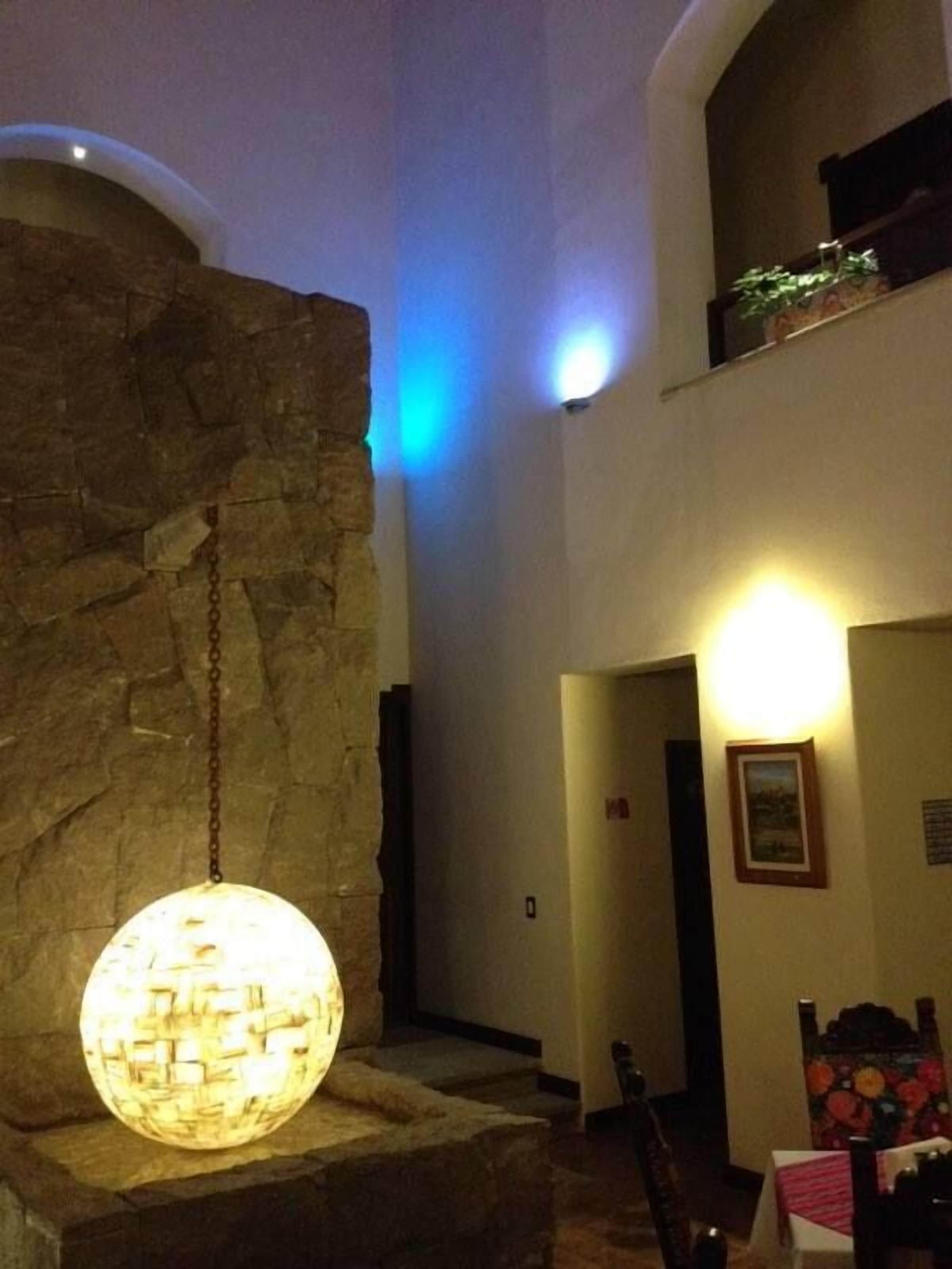 A lobby with a stone wall, a hanging spherical light fixture, and a staircase leading to an upper level.
