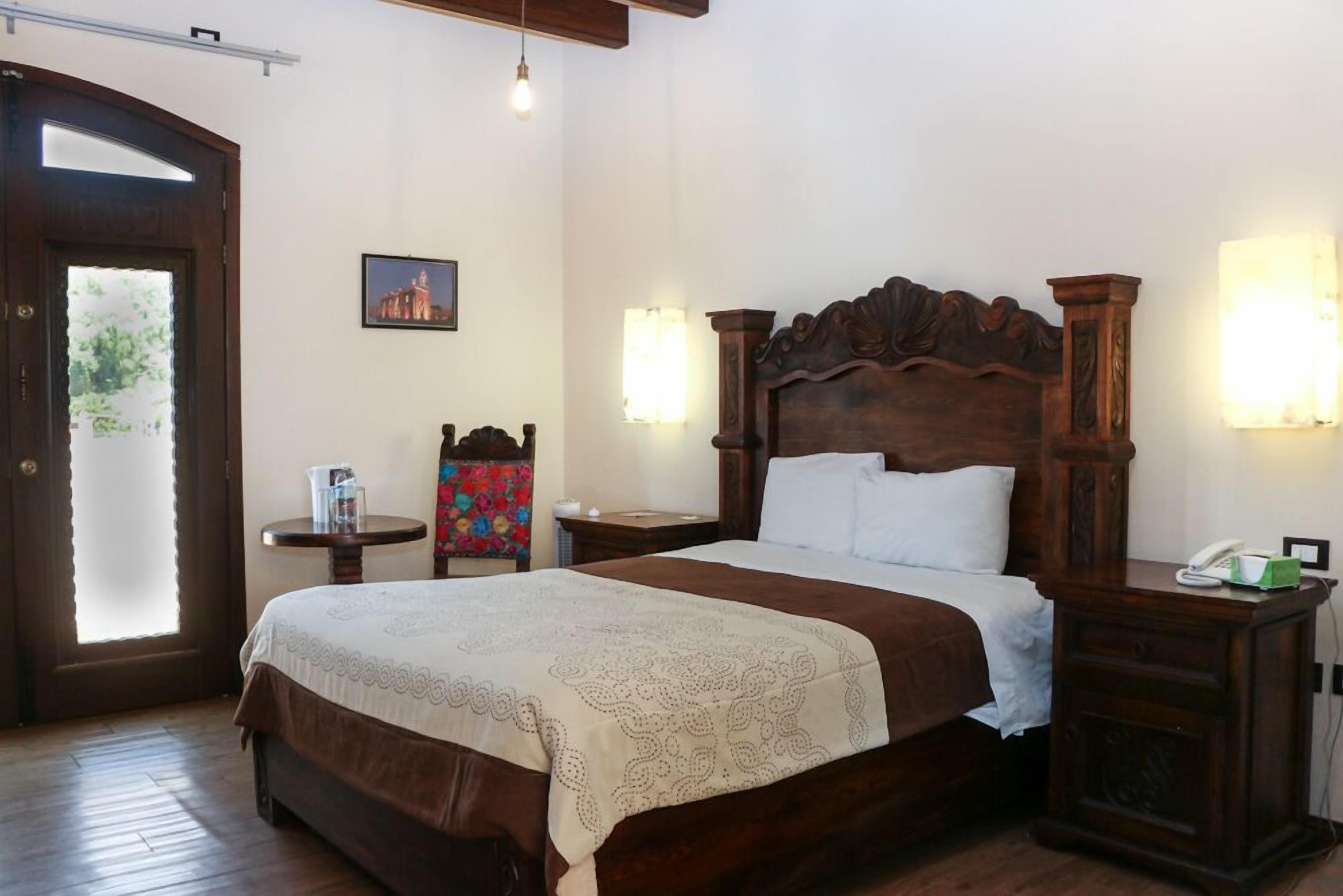 A bedroom with a wooden bed, two bedside tables, a chair, and a picture on the wall.