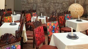 A dining area with wooden chairs and tables, some with floral upholstery. - Hotel Xelhua (San Pedro Cholula)