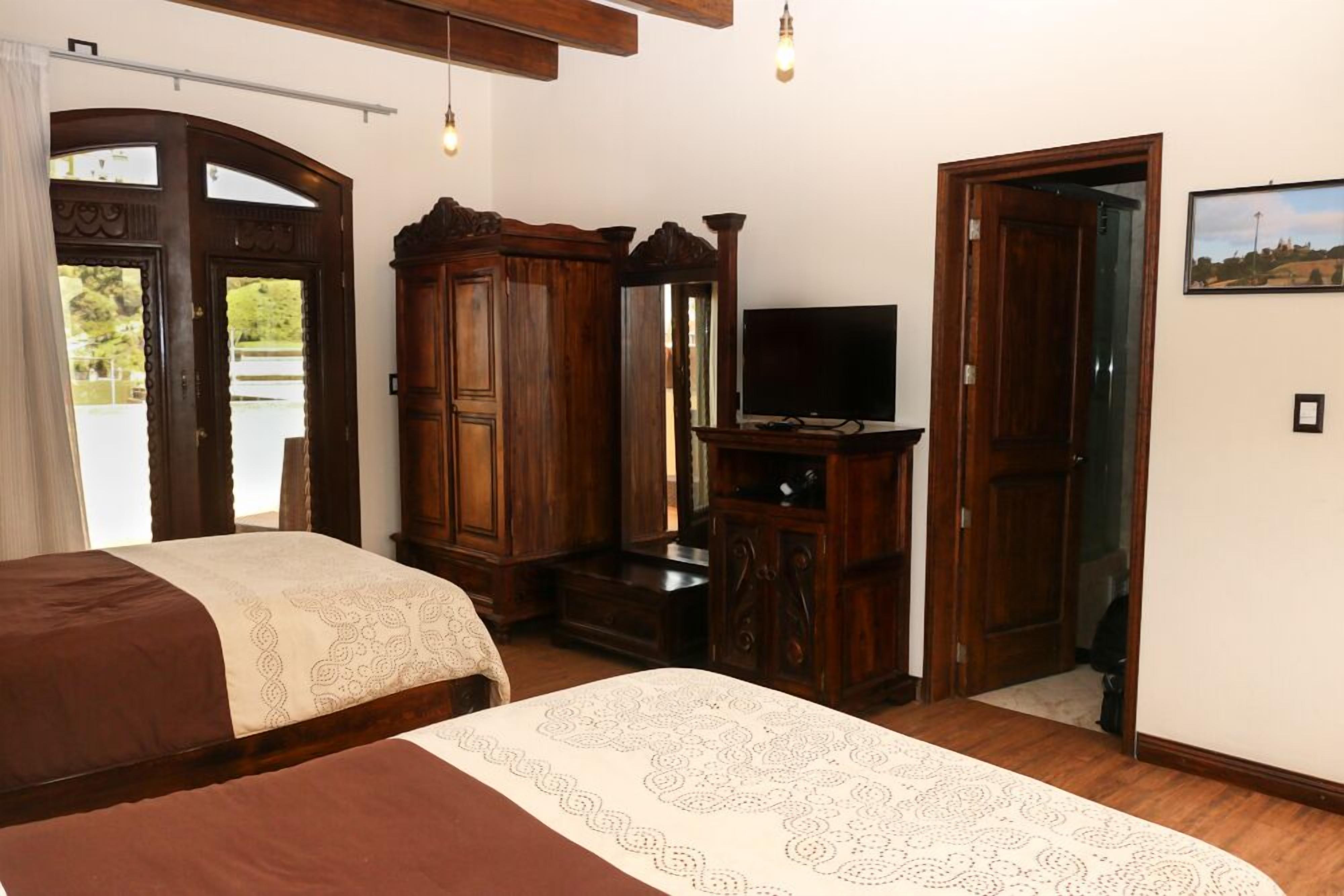 Un dormitorio con cama, armario de madera, televisor y un cuadro en la pared.