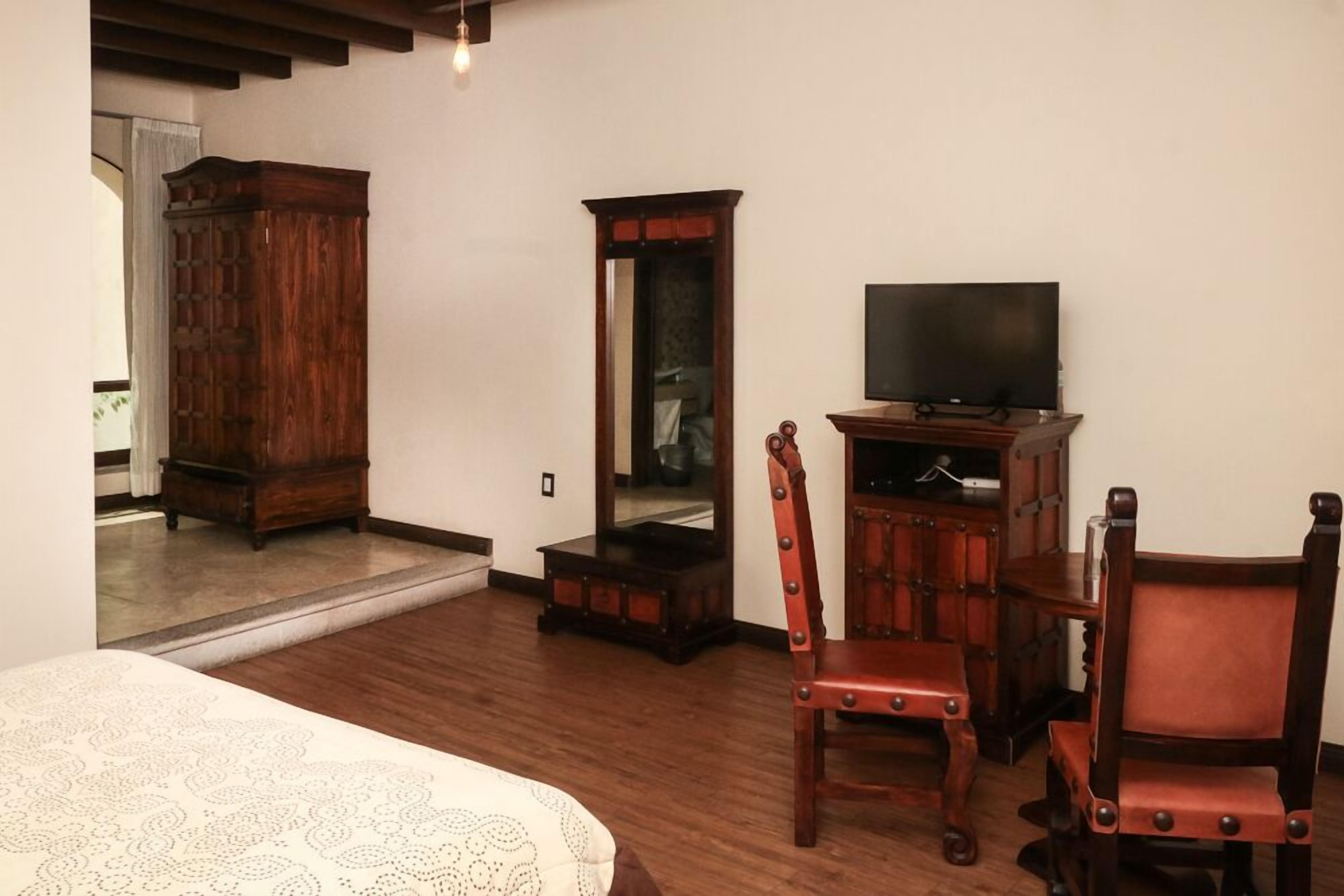 Una habitación con cama, muebles de madera, televisión y espejo.