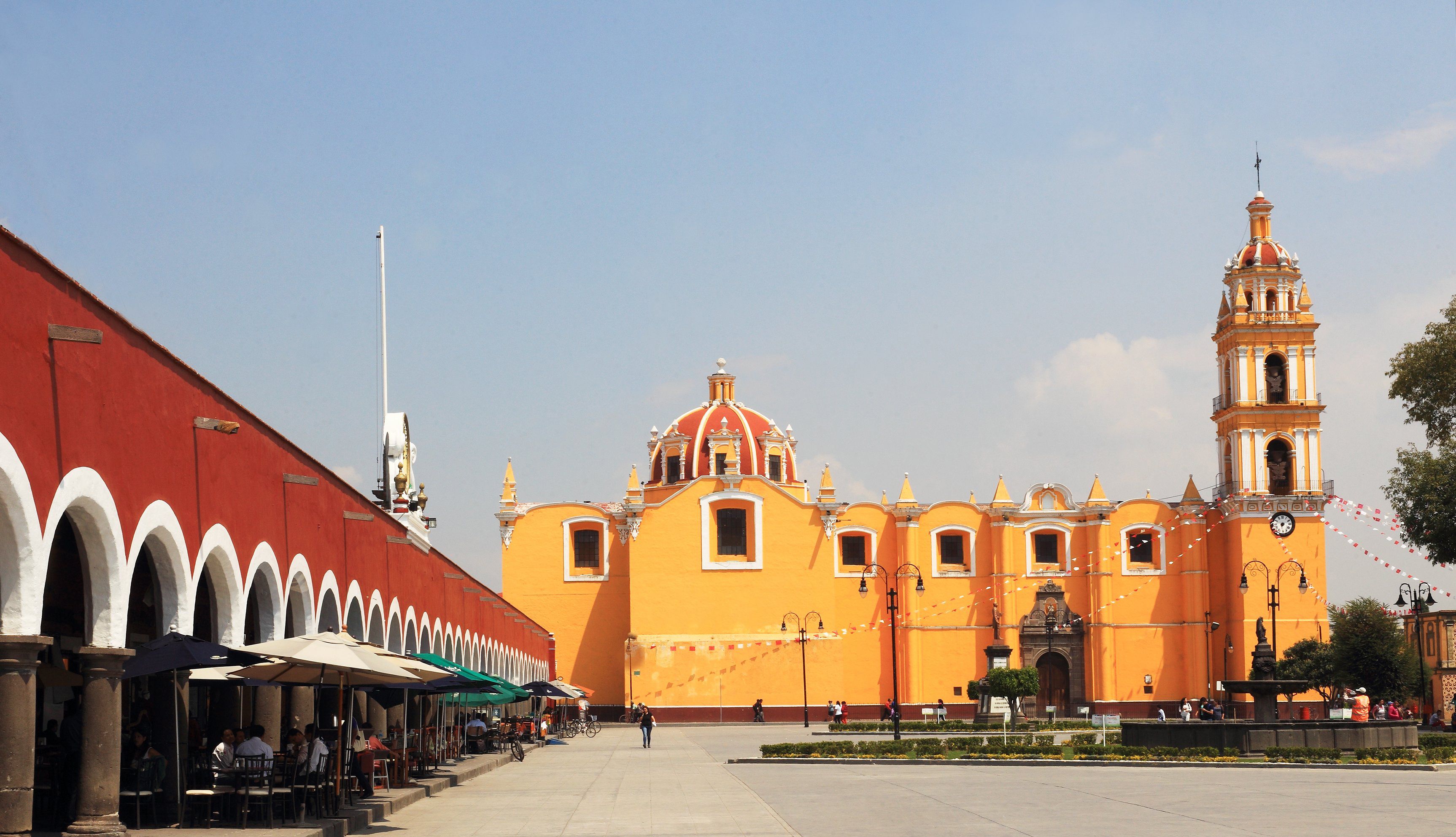 A historic building with a prominent dome and bell tower, surrounded by a plaza with outdoor seating and a fountain.