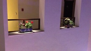 A multi-level building with arched windows and balconies, some with potted plants. - Hotel Xelhua (San Pedro Cholula)