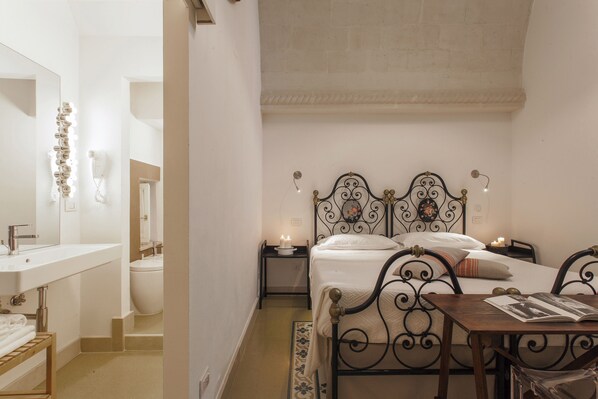 Une chambre à coucher comprenant un lit, des tables de chevet, une commode, un miroir et une salle de bain avec un lavabo et des toilettes.