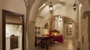 A rustic interior with stone arches, a dining area with a wooden table and benches, and a cozy fireplace. - Casa Diva (Matera)