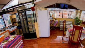 Een kleine keuken met een fornuis, koelkast en een eethoek met stoelen en een tafel.