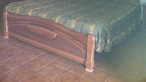 Un dormitorio con cama de madera, una mesita de noche y un armario.