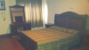 Un dormitorio con cama de madera, una mesita de noche, un aparador y un espejo.