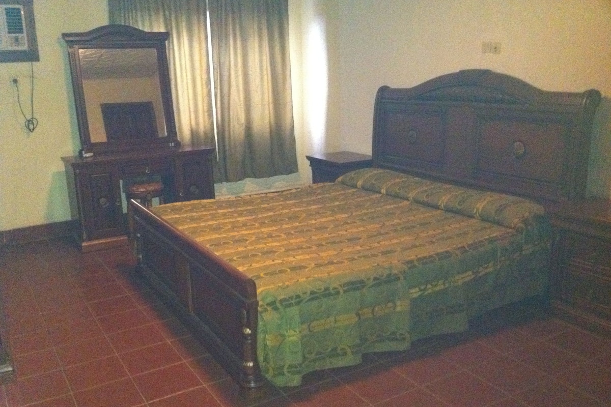 Un dormitorio con cama de madera, una mesita de noche, un aparador y un espejo.
