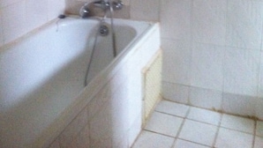 Un baño con bañera, ducha y una toalla colgada en la pared.