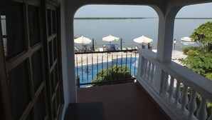 Un balcón con vista a una piscina y un cuerpo de agua.