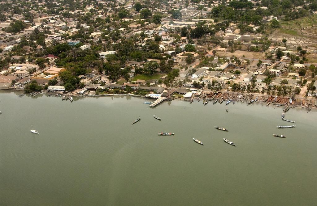 Vista aérea de un pueblo costero con un puerto deportivo, barcos y edificios residenciales.