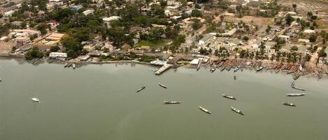 Vista aérea de un pueblo costero con un puerto deportivo, barcos y edificios residenciales.