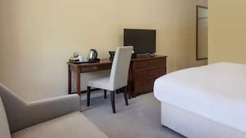A hotel room with a bed, a desk with a chair, a television, and a dresser.