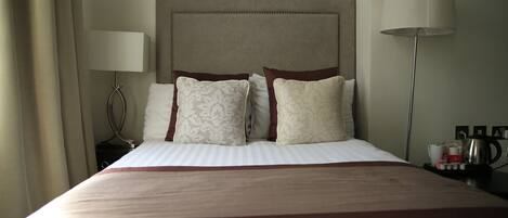 A neatly made bed with a striped bedspread, a headboard with a decorative pattern, and two bedside lamps.