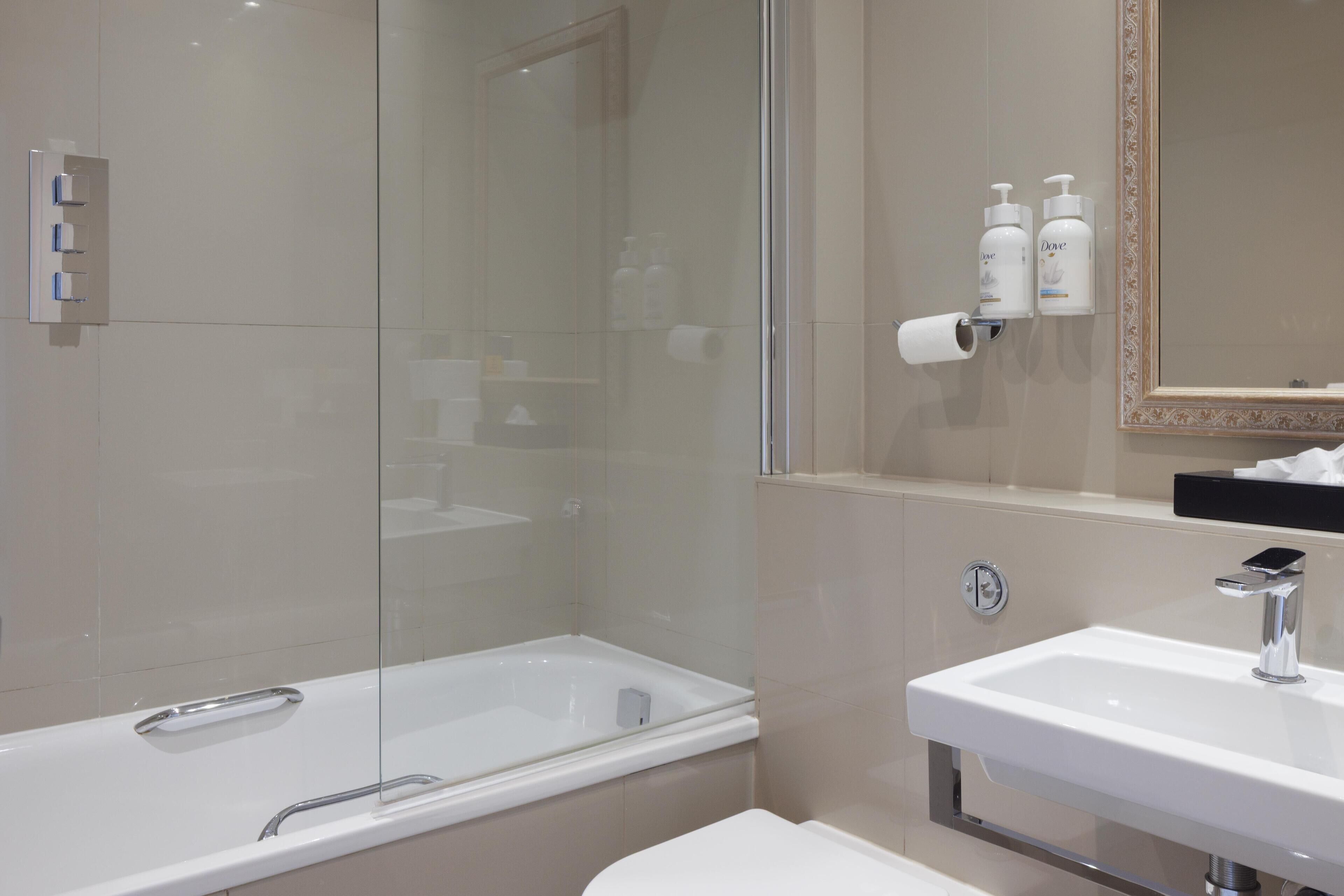 Une salle de bain moderne avec une douche à parois de verre, un lavabo blanc et des articles de toilette fixés au mur.