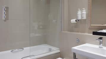 A modern bathroom with a glass-enclosed shower, a white sink, and toiletries on the wall.