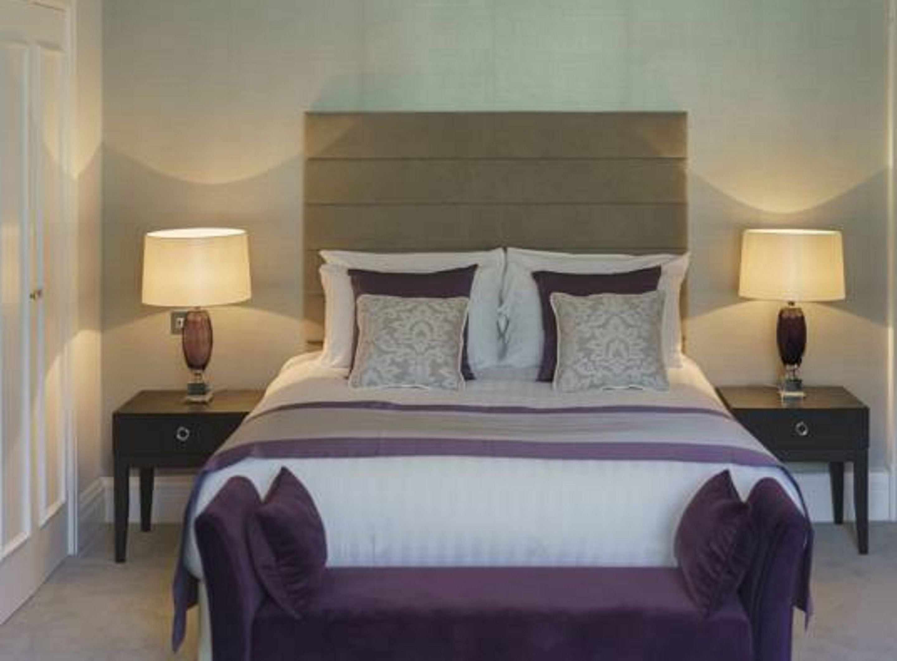 A neatly arranged bedroom with a large bed, two bedside tables, and two lamps.