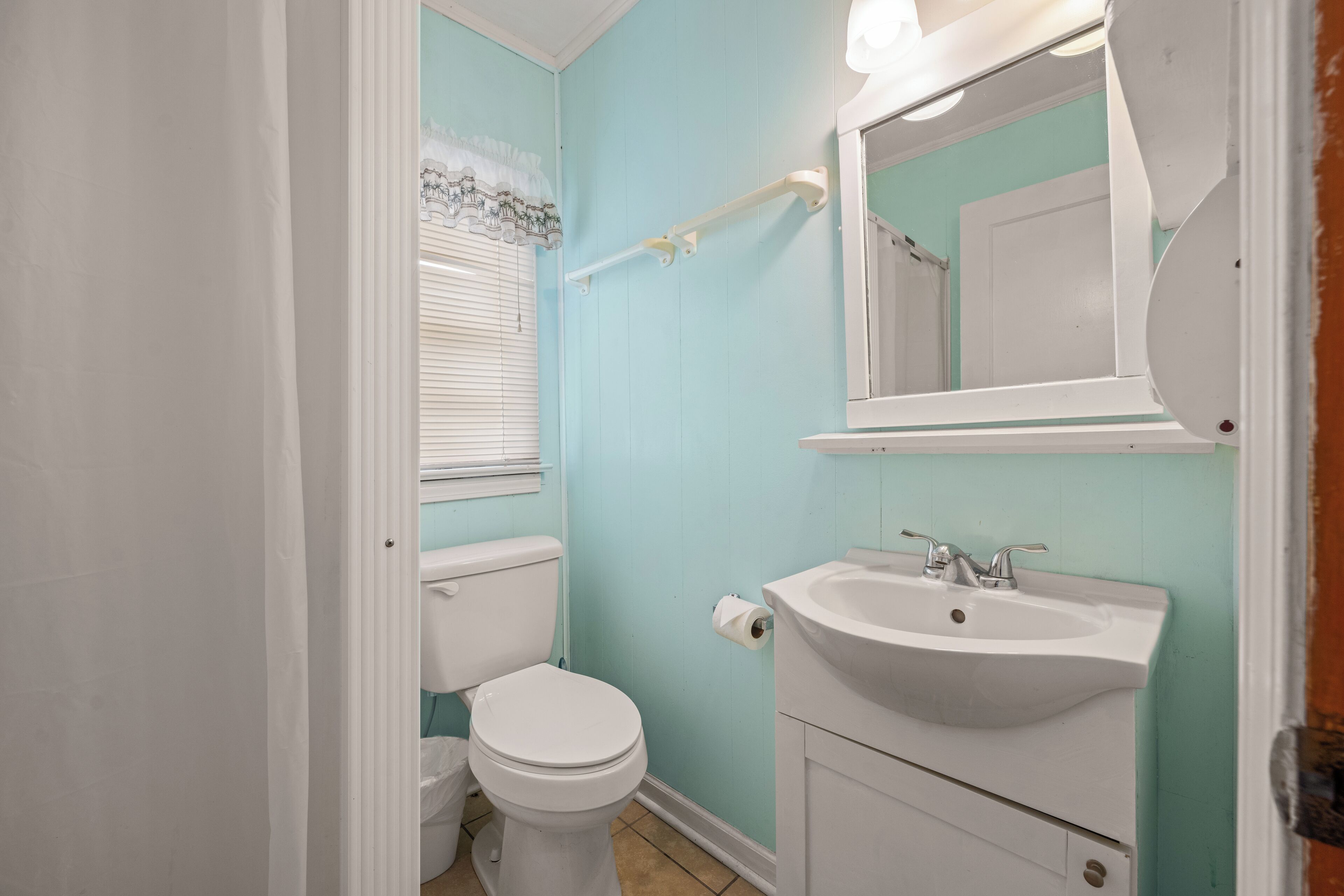 Un baño con inodoro, lavamanos y espejo.