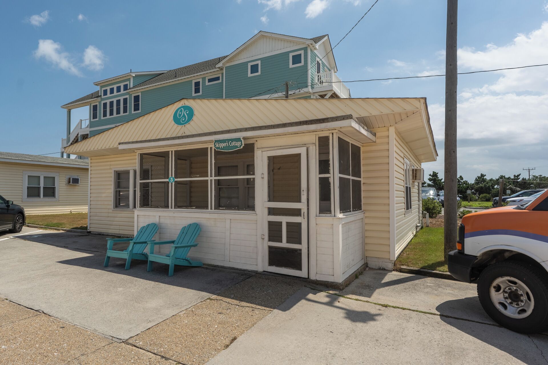 A small, single-story building with a porch and two chairs.