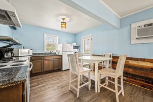 Cocina compacta con zona de comedor, que incluye estufa, microondas, refrigerador y una mesa redonda con sillas.