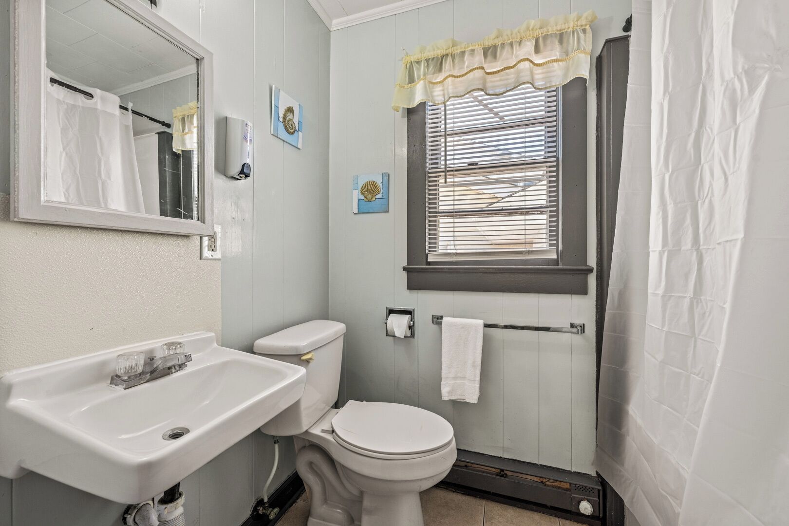 A bathroom with a sink, toilet, and window with blinds.