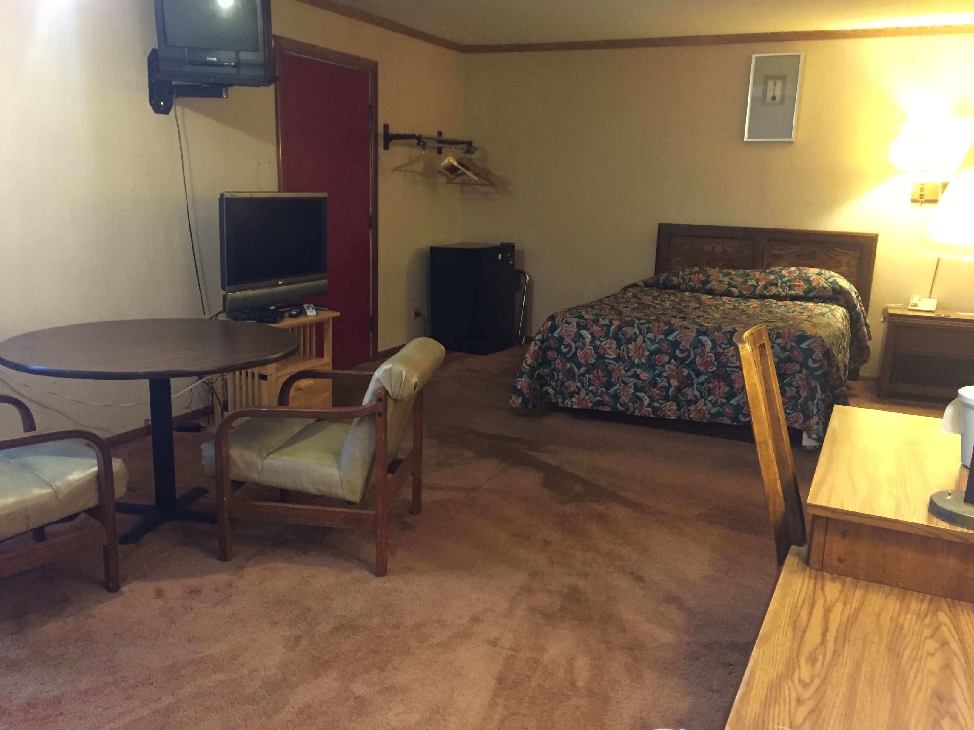 Ein Hotelzimmer mit Bett, Schreibtisch, Stuhl, Fernseher und Lampe.