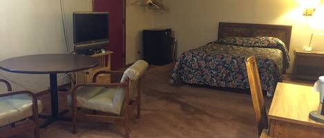 Ein Hotelzimmer mit Bett, Schreibtisch, Stuhl, Fernseher und Lampe.