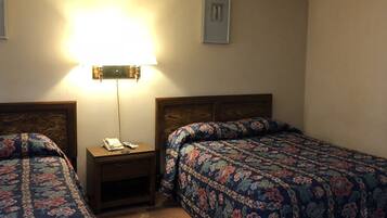 A hotel room with two beds, a nightstand with a lamp, and a framed picture on the wall.