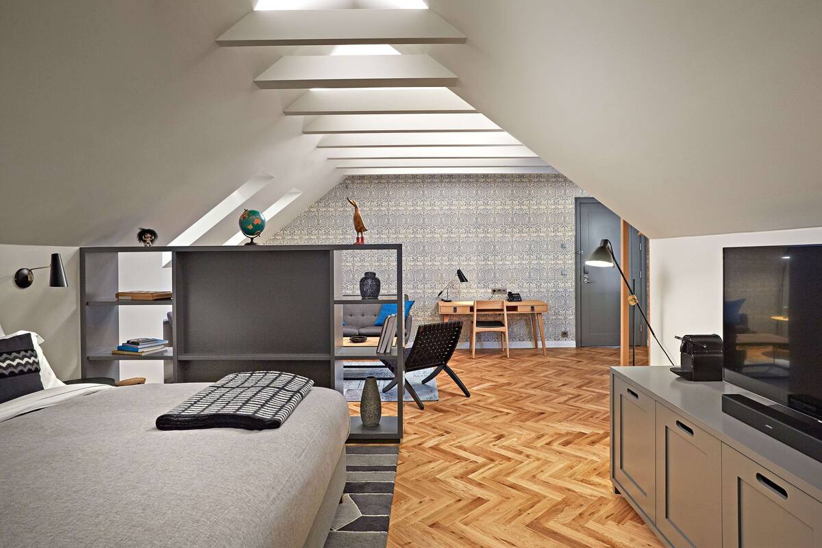 Een moderne loft slaapkamer met een verhoogd bureau, een groot bed en een televisie.
