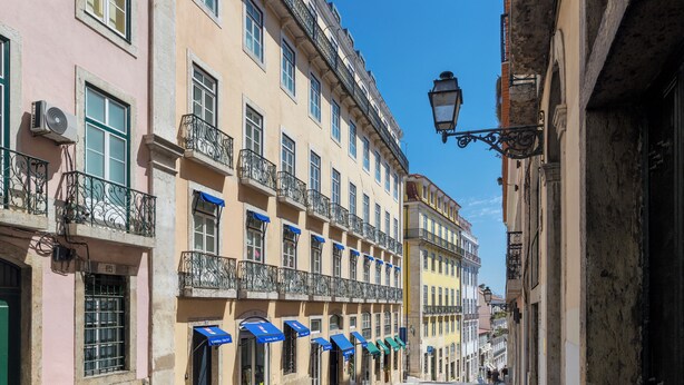 A street with buildings featuring balconies, awnings, and a cobblestone road. - Martinhal Lisbon Chiado (Lisbon)