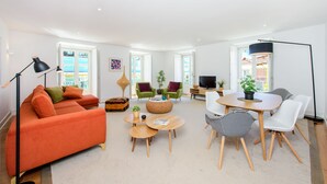 A modern living room with a sofa, coffee table, chairs, and a TV. - Martinhal Lisbon Chiado (Lisbon)