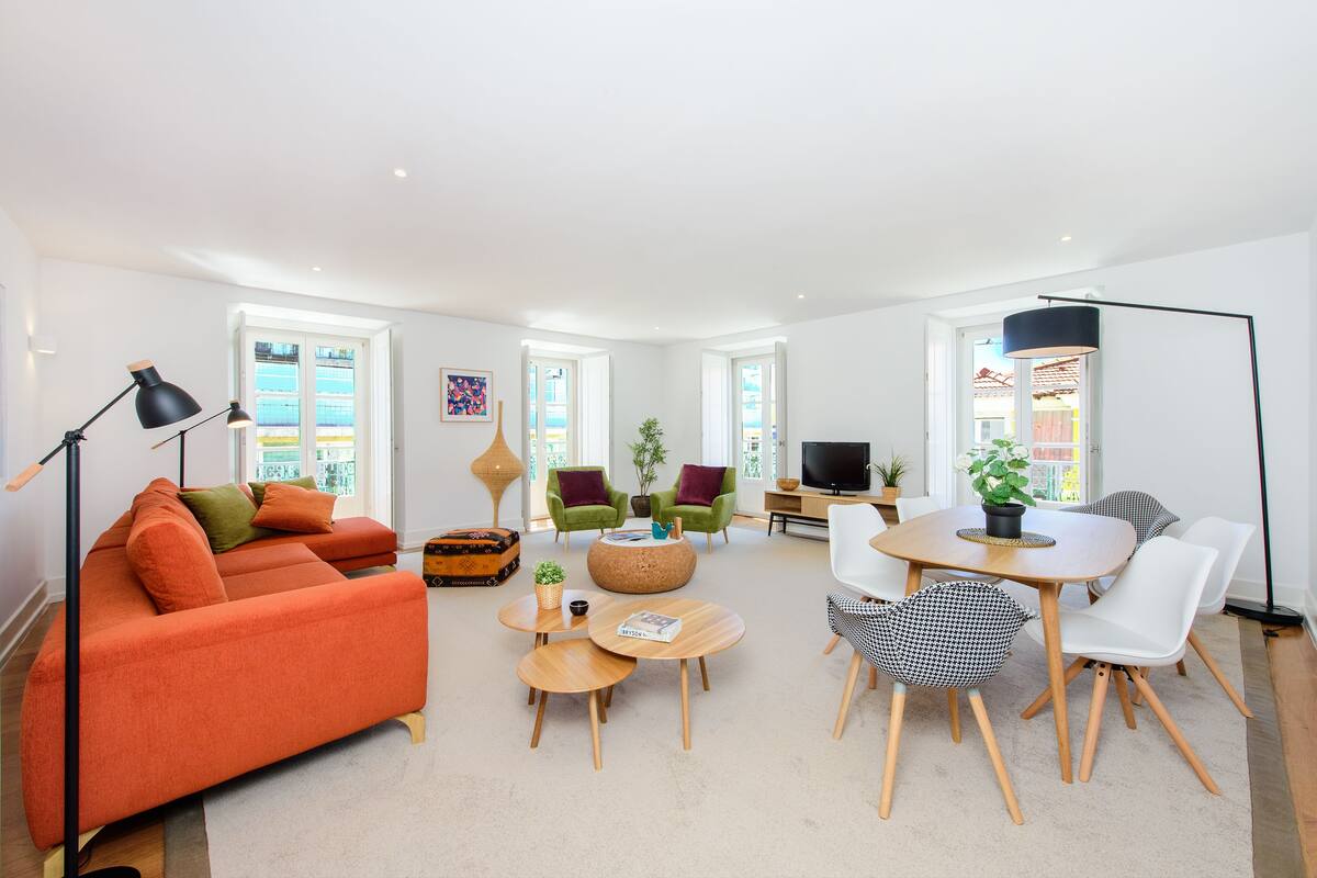 A modern living room with a sofa, coffee table, chairs, and a TV.