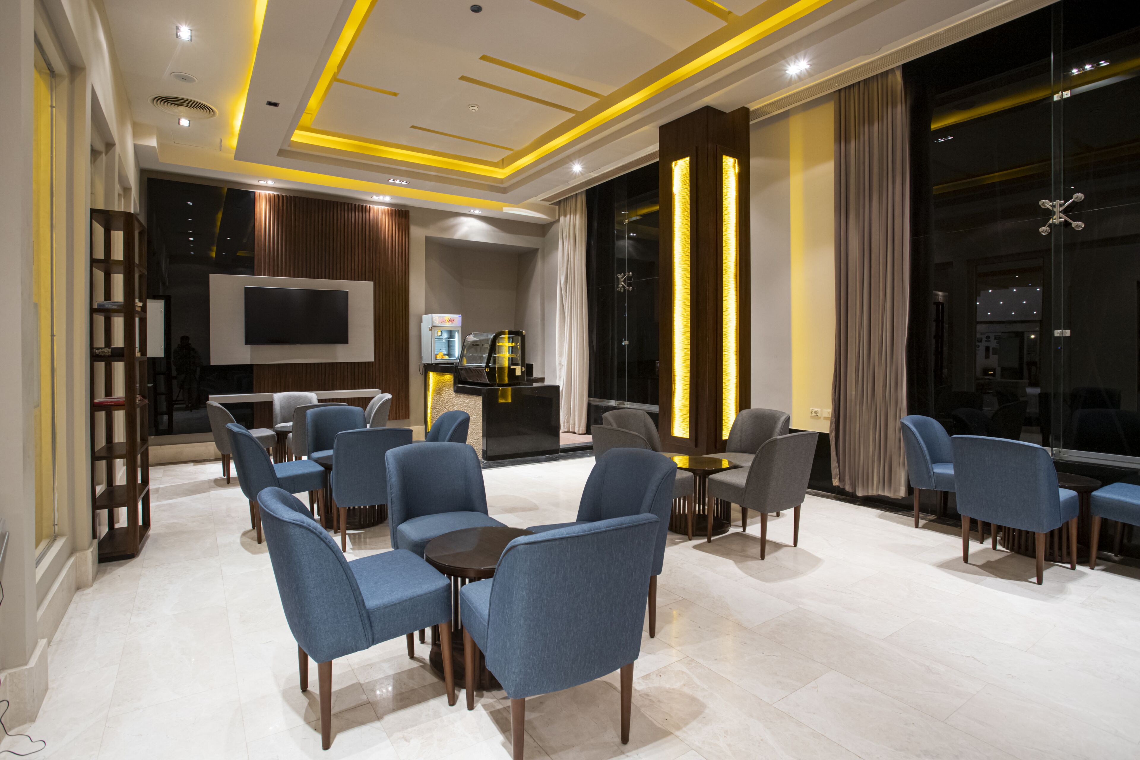 Un moderno vestíbulo de hotel con una zona de estar, un televisor de pantalla plana y una recepción.