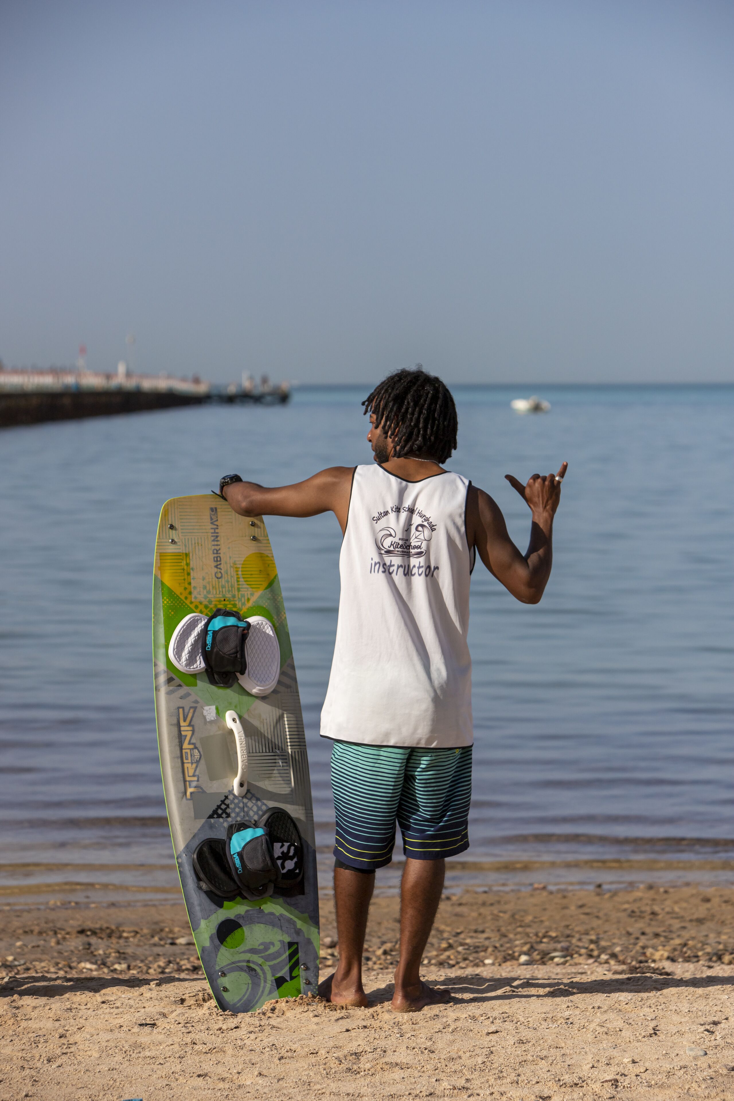 A person standing on a sandy beach holding a surfboard.