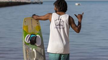 A person standing on a sandy beach holding a surfboard.