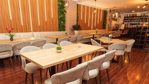 A modern restaurant with wooden flooring, cushioned seating, and a bar area with wine bottles. - Hotel Libertador (Loja)